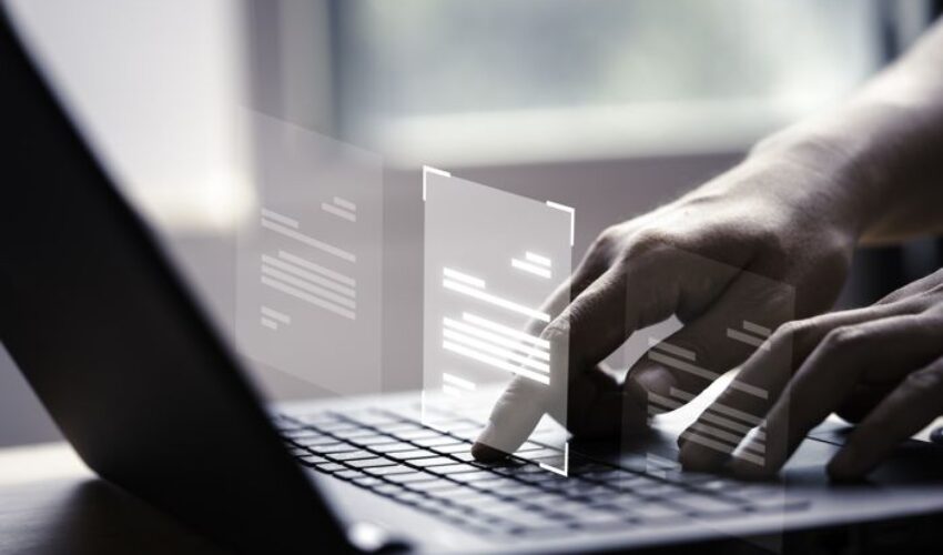 Hand using laptop computer with virtual screen and document for online approve paperless quality assurance and ERP management concept.